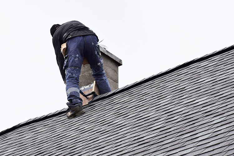 Man on roof woorking on chimney flashing