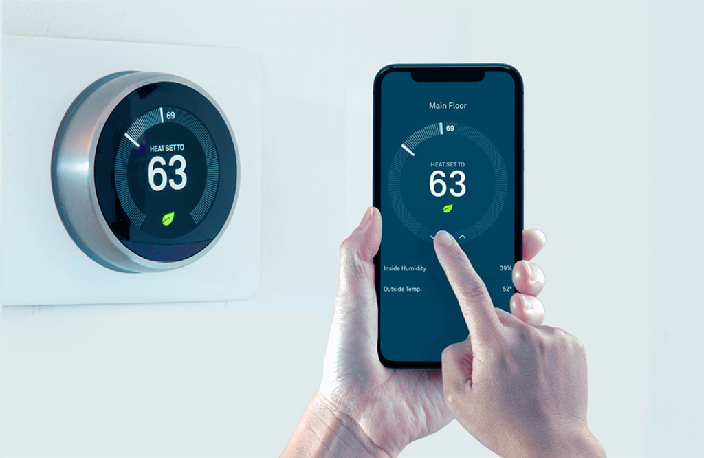 Man holds a smart phone and sets the temperature on his smart thermostat
